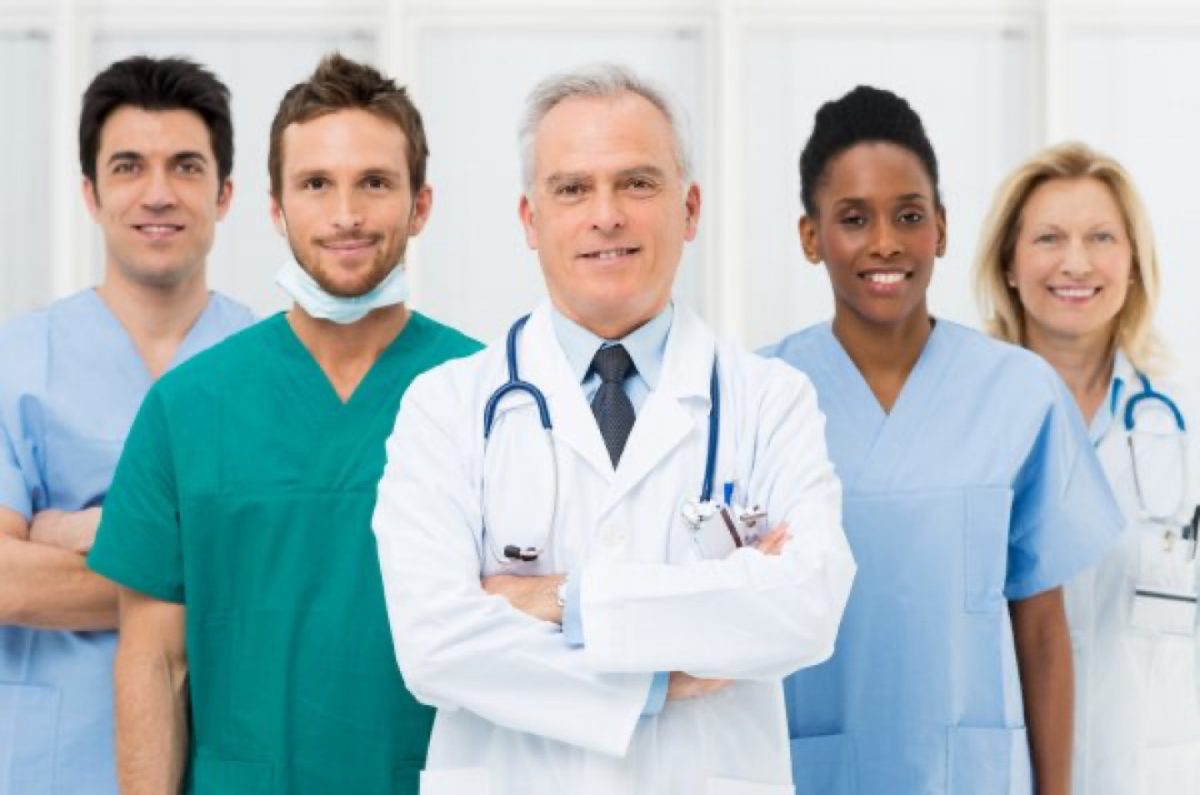 A team of providers flanking a physician in a white coat.
